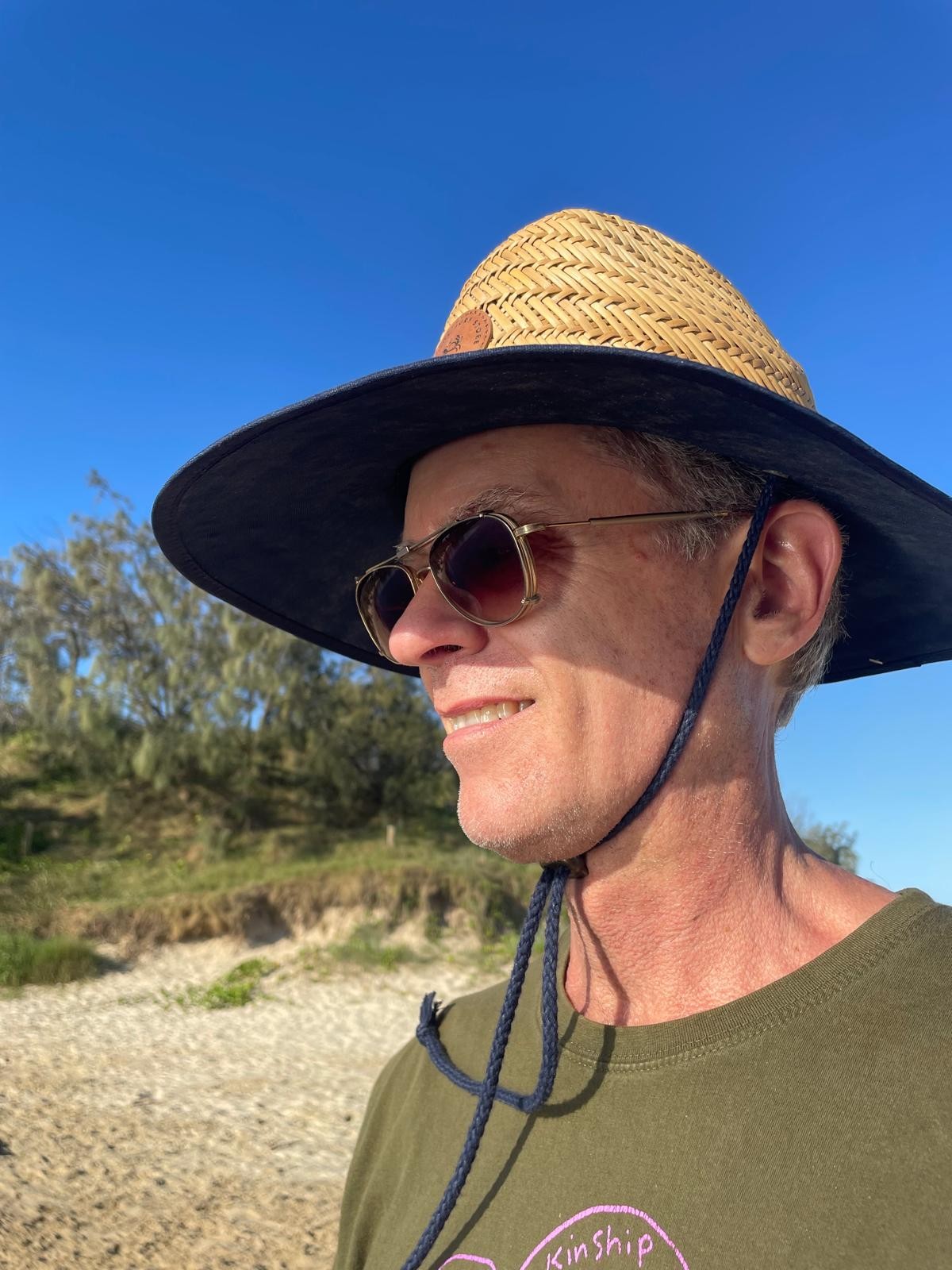 Jeremy in a straw hat on the coast, looking out