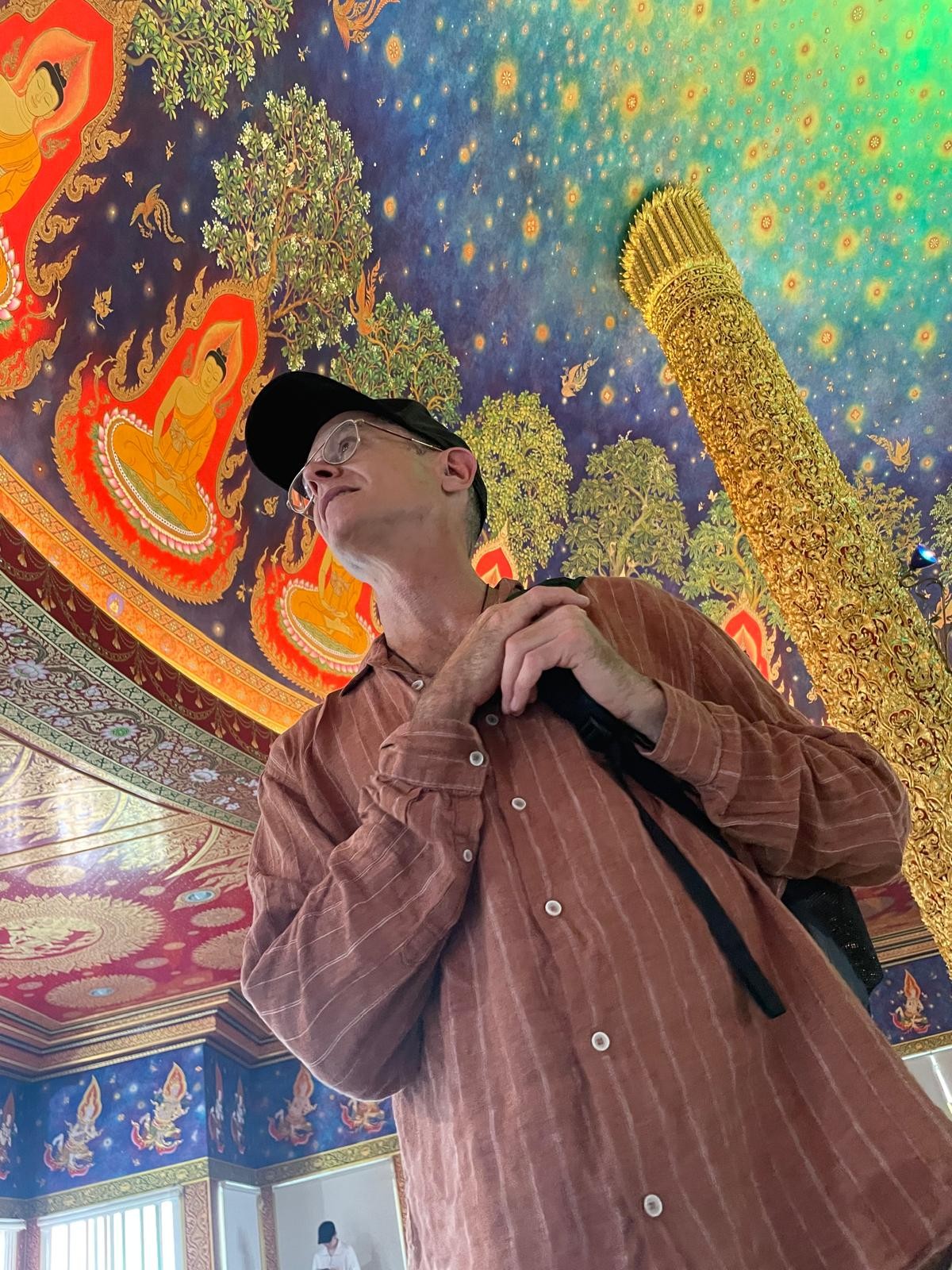 Jeremy looking up at an elaborately painted temple ceiling
